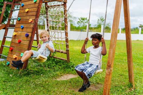 Preview: Two boys play on swings, one smiling while the other looks contemplative, enjoying their day