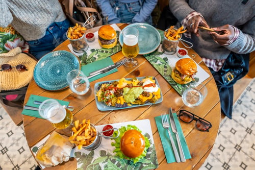 Preview: Friends enjoying burgers, nachos, and fries at restaurant table