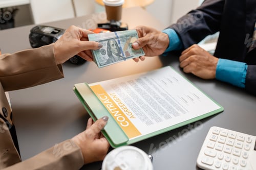 Preview: A businessperson and client are reviewing and signing a car sales contract at a desk