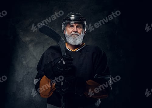 Preview: Aged hockey player dressed in black sportswear holding stick