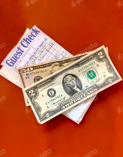 Preview: Overhead view of check with money on top of it on a red background at the cafe.