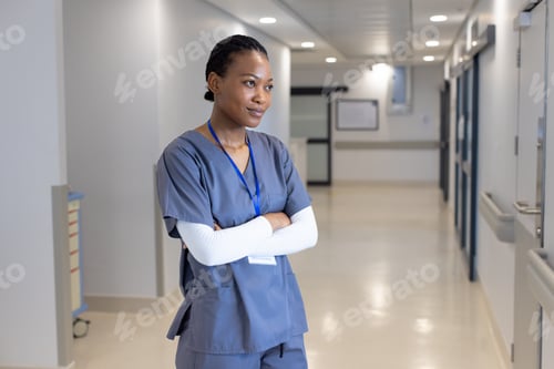 Preview: Happy african american female doctor standing in hospital corridor