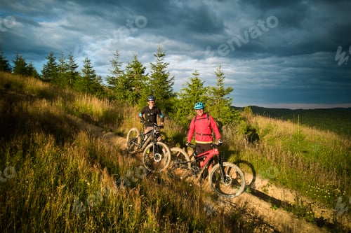 Preview: Two cyclists men resting on the top of hill while riding electric bikes outdoors.