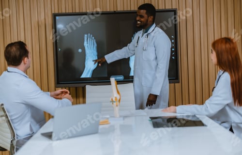Preview: Surgeon and radiologist discuss Pt's ankle's MRI for treatment plan. Multicultural boardroom meeting