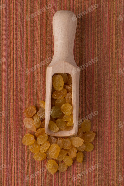 Preview: Wooden scoop with golden raisins