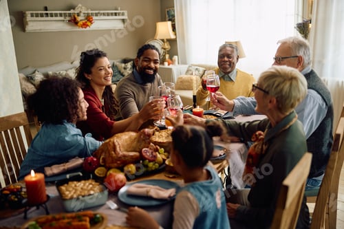 Preview: Happy multigeneration family toasting while celebrating Thanksgiving at dining table.