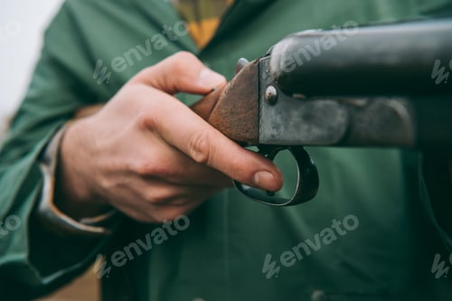 Preview: Cropped image of hunter loading a gun