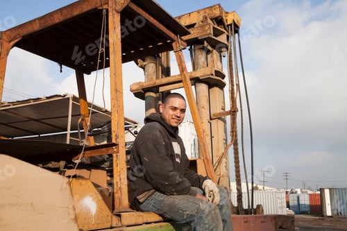 Preview: Man on construction site sitting on heavy machinery