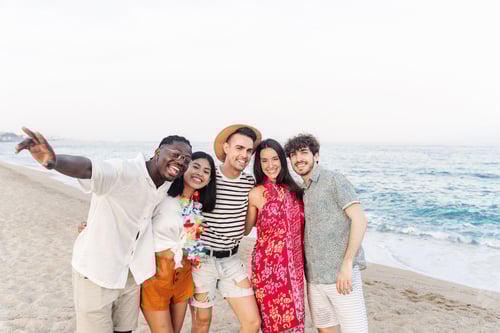 Preview: Happy multi ethnic friends hanging out having fun outdoors on the beach
