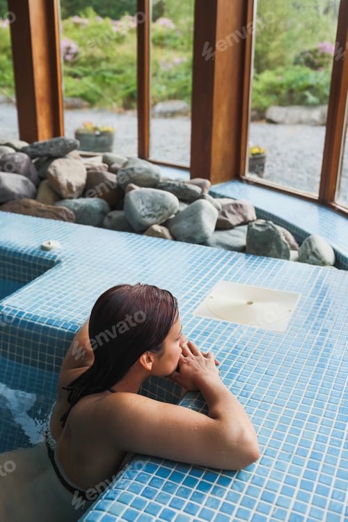 Preview: Brunette relaxing in a jacuzzi in a spa looking out the window