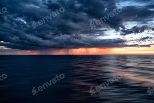 Preview: Dark clouds of the sunset sky over the dark water of the ocean