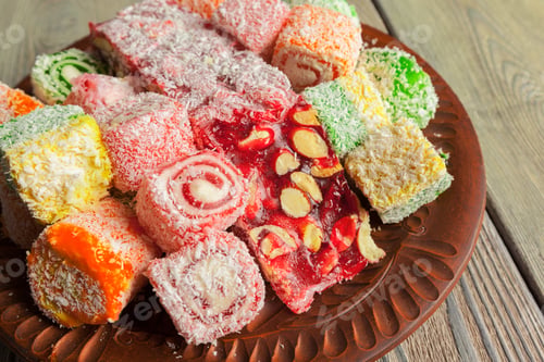 Preview: Colorful Turkish delight on a wooden plate during a gathering in the afternoon