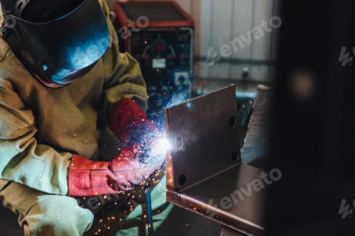 Preview: Industrial worker or welder wears protective mask and gloves erects technical steel on factory