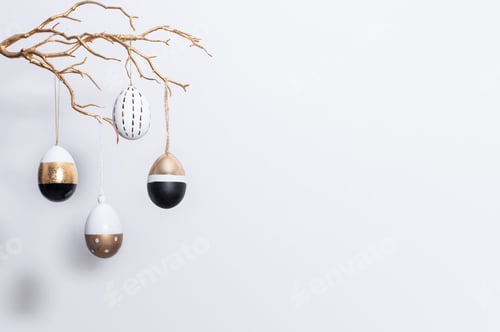Preview: Decorative golden, black and white Easter eggs hang on a golden branch. Easter decorations.