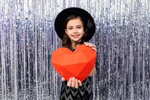 Preview: european cute girl holding a red paper heart on a shiny background
