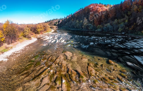 Preview: River rapids near mountain foothill with terracotta forests