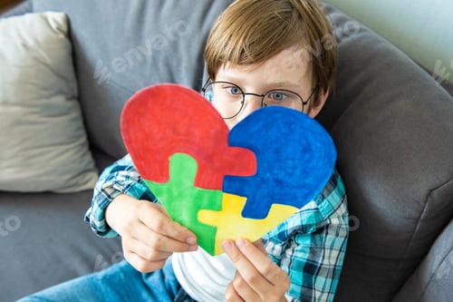 Preview: Preteen boy holding puzzle jigsaw heart shape, child mental health concept, world autism awareness