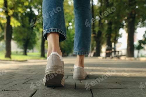 Preview: Woman in stylish sneakers walking on city street, closeup