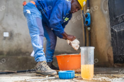 Preview: Young African blue collar worker washing the filters' containers. Water filtration concept