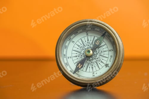 Preview: Antique navigational compass with an orange background.