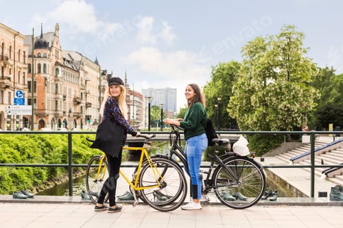 Preview: Two young women standing with bicycles on footbridge