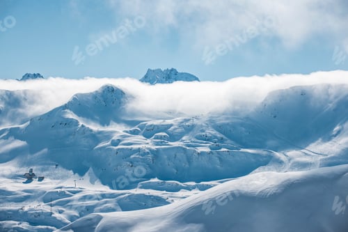 Preview: Layered clouds roll over Arlberg peaks in a dramatic winter mountain scene