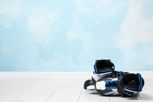 Preview: Inline roller skates on floor near color wall. Space for text