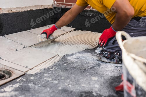 Preview: worker laying tiles on the floor with cement