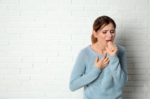 Preview: Woman suffering from cough near brick wall. Space for text