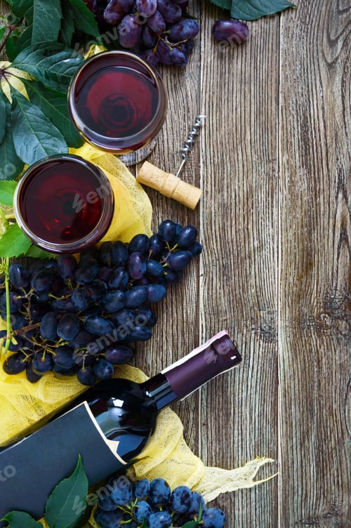 Preview: Wineglasses with red wine, bottle, corkscrew, blue grapes, leaves on a wooden table