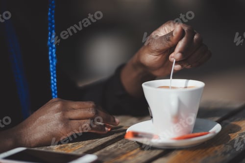 Preview: Black woman stirring sugar in a cup