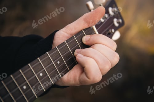 Preview: A man plays the ukulele guitar in nature, close-up fingers clamp the strings.