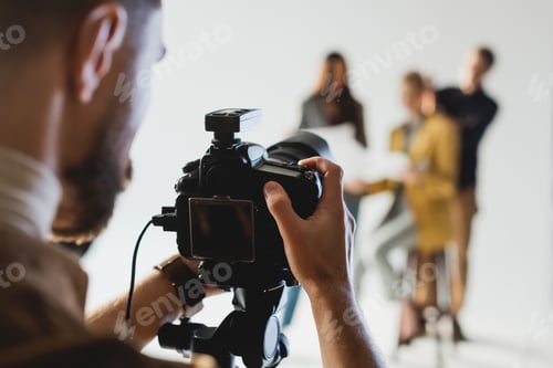 Preview: selective focus of photographer taking photo of producer, model and hairstylist