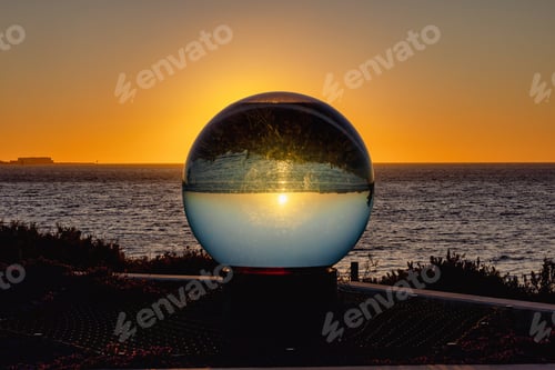 Preview: a glass ball on top of a field by the water