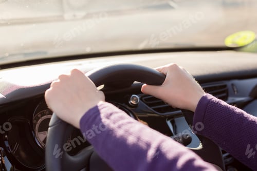 Preview: Female hands on steering wheel while driving a car