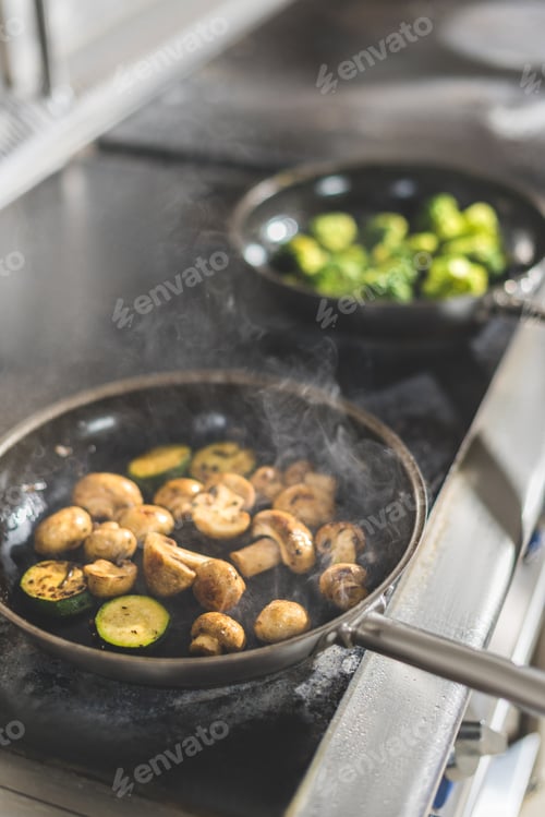 Preview: vegetables on frying pans on stove at restaurant kitchen