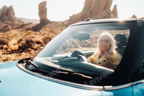 Preview: Girl in yellow dress enjoying a road trip in a convertible through a deserted valley with mountains
