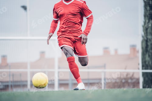 Preview: African soccer player with red outfit playing soccer.