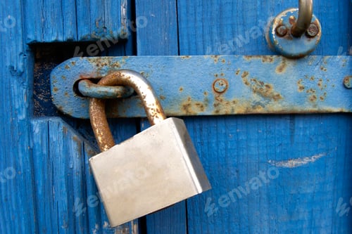 Preview: Old Lock on Blue Wood Door. Old-fashioned latch on the door, retro style. Old closed padlock rusty