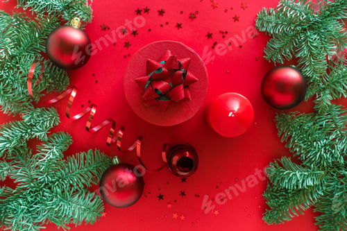 Preview: Christmas composition made of christmas gift, candle, pine branches, baubles on red surface. Merry
