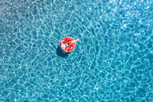 Preview: Aerial view of a woman swimming with red swim ring in blue sea