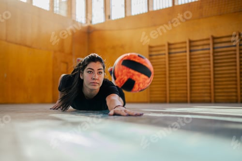 Preview: A young sportswoman in action with a ball on volleyball court.
