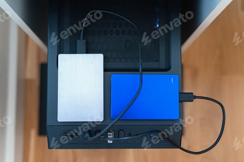 Preview: Two external SSD hard drivers connected to stationery computer in home office.