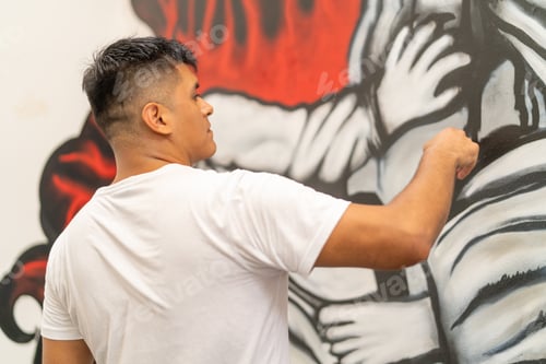 Preview: Young latin man artist painting public mural