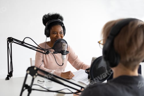 Preview: black woman wearing headphones and with microphone recording podcast or audio content for radio