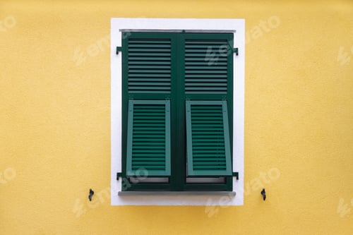 Preview: green wooden window with shutters in a white frame on the yellow wall