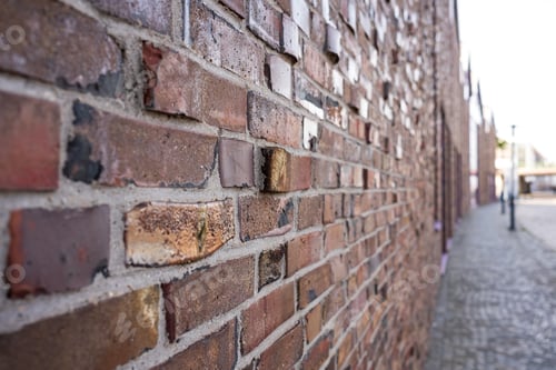 Visualização: Parede de tijolos de um prédio antigo na rua de uma aconchegante cidade provinciana.