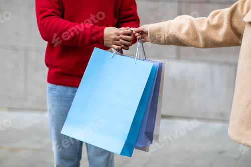 Preview: Unrecognizable man and woman holding bright shopper bags outdoors, mockup for your brand logo design