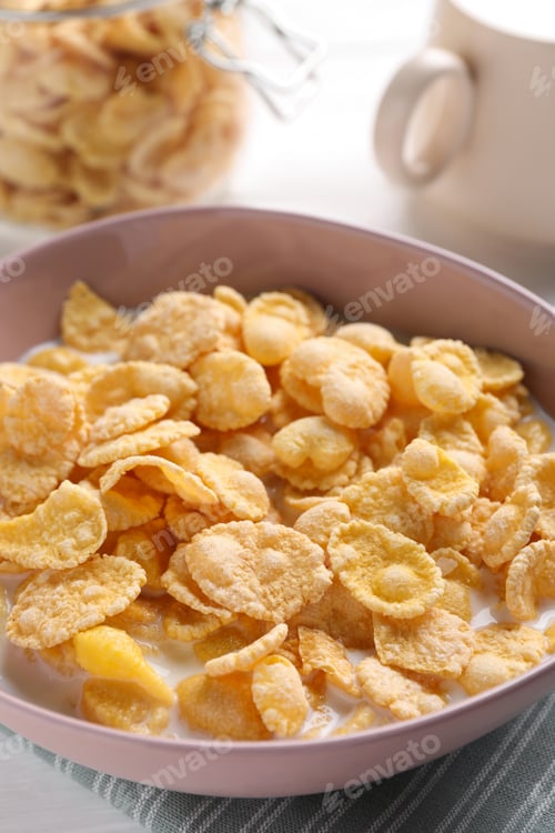 Preview: Tasty cornflakes with milk in bowl on table, closeup
