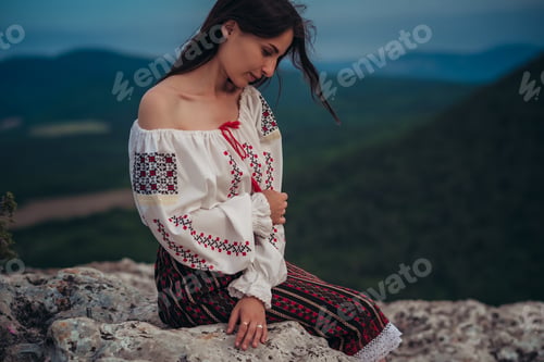 Preview: Atractive woman in traditional romanian costume on mountain green blurred background
